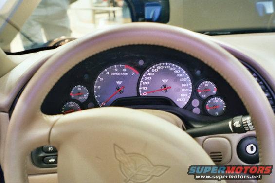 Interior dashboard with beige steering wheel and gauges, a Corvette emblem