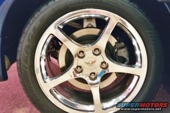 Chrome five-spoke wheel with a Corvette emblem on a blue vehicle