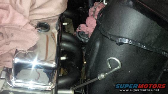 Engine bay detail showing chrome valve cover, black exhaust manifold, and part of a black shroud