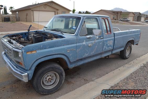 Blue pickup truck with hood open, parked on street. Appears to be a Ford F-Series from the early 1980s