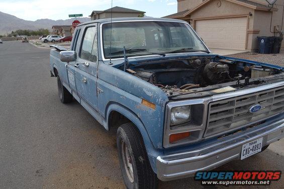 Blue 1981 Ford F-250 pickup truck, hood open, parked on street