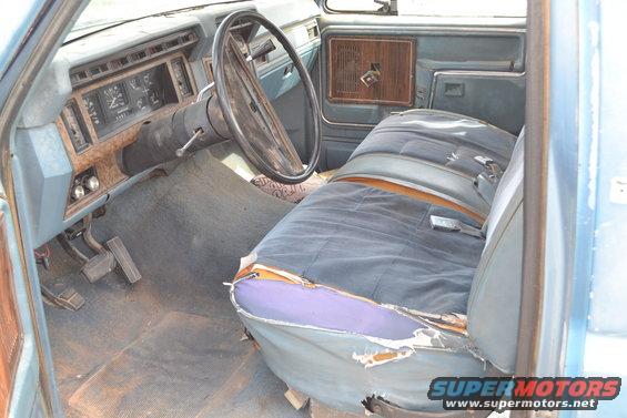 1981 Ford F-250 interior showing worn blue seats, dashboard with gauges, and steering wheel