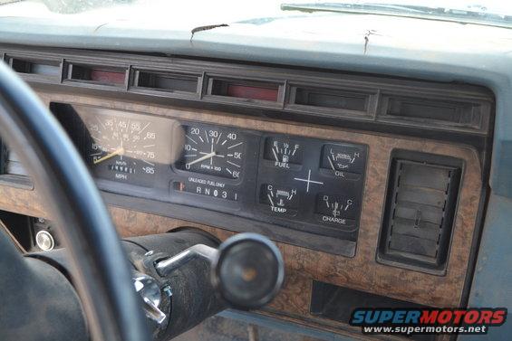 1981 Ford F-250 dashboard with woodgrain trim, showing speedometer, tachometer, fuel, oil, temperature, and charge gauges