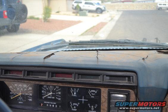 Cracked dashboard and view through windshield of other vehicles outside