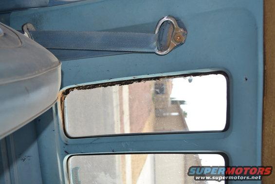 Interior view of a light blue door panel with a seat and window. The window shows a reflection of buildings