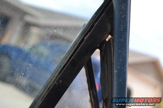 Close-up of a vehicle's interior windshield frame and glass, showing wear and dust