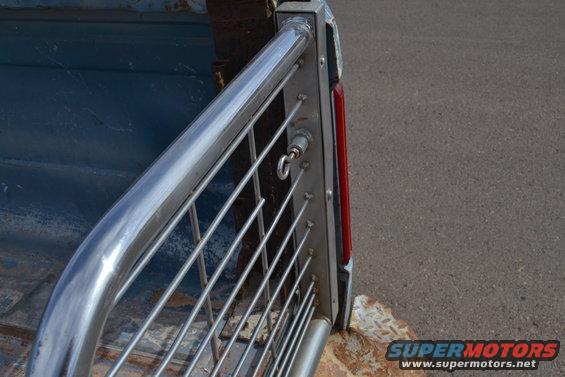 Chrome bed rail and red taillight on a blue truck bed, with a metal grate