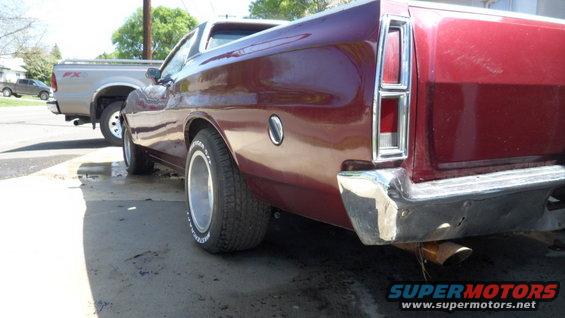 Rear quarter view of a red 1972 Ford Ranchero parked next to a silver pickup truck