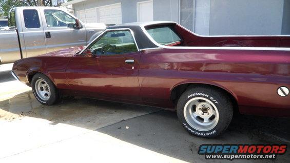 Maroon 1972 Ford Ranchero with a black vinyl top, parked next to a silver pickup truck