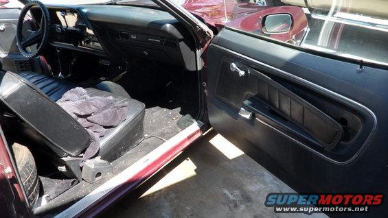 Maroon 1972 Ford Ranchero interior with black seats and door panels, driver's side door open