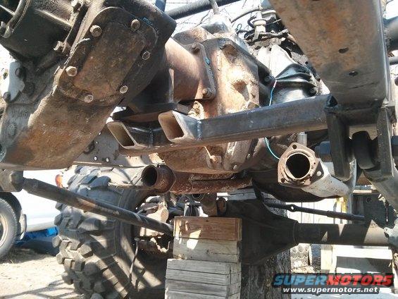 Close-up of vehicle drivetrain and suspension parts, including differential and exhaust pipe