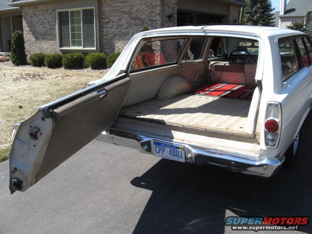Rear view of a white 1966 Ford Falcon wagon with the tailgate open. Red blanket on the floor