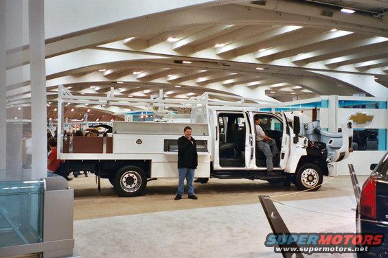 White utility truck with a crew cab and a service body, viewed from the front three-quarter angle