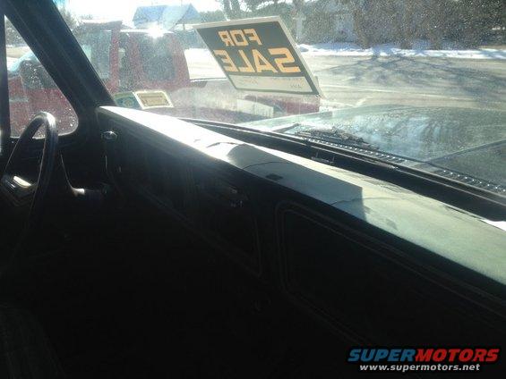 Interior view of a vehicle with a "FOR SALE" sign on the windshield; another vehicle is visible outside