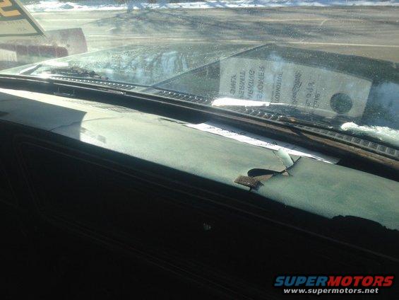 Cracked dashboard and windshield interior with a sticker on the glass