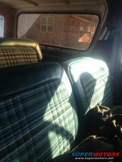 Green plaid and dark green vinyl interior seats with sunlight streaming through the rear window