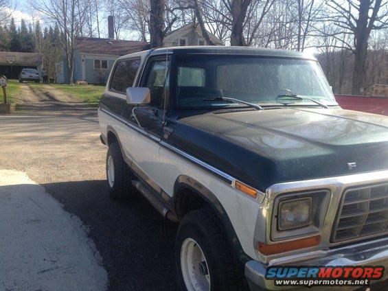 Two-tone green and white Ford Bronco parked outside a house