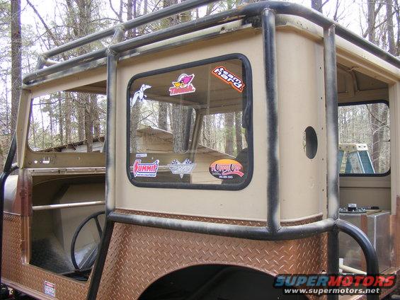 Off-road vehicle with roll cage and stickers on window. Diamond plate fender