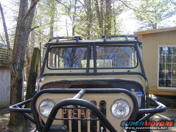 Tan Jeep CJ-5 with a roll cage and brush guard, showing "FREAK" on the grille