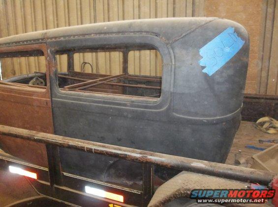 car body on trailer, blue tape on rear fender says SOLD