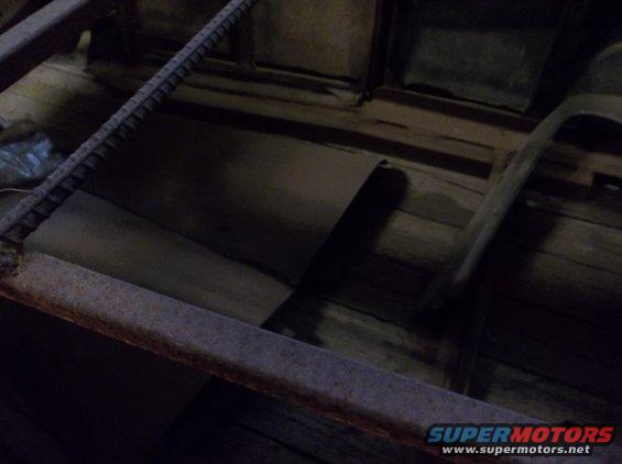 Interior view of a rustic wooden structure with metal bracing and what appears to be a rolled-up tarp