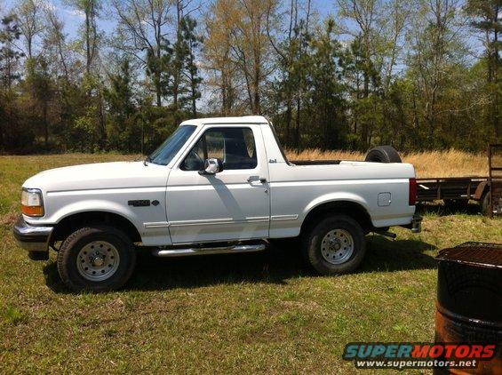 1993 Ford Bronco parked on grass with a trailer behind it