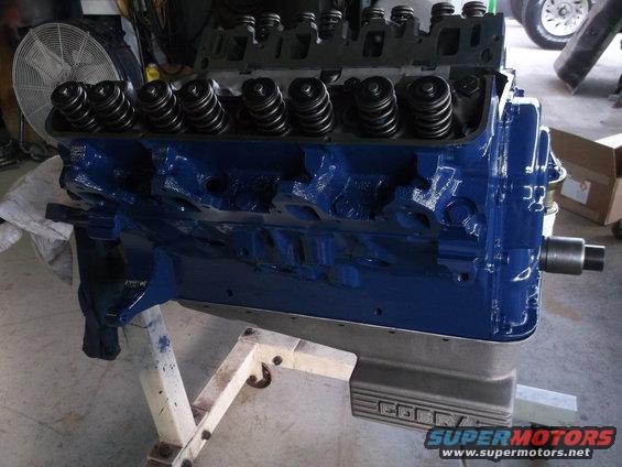 Blue engine block with valve springs visible, mounted on a stand. 'COBRA' text is visible on the oil pan