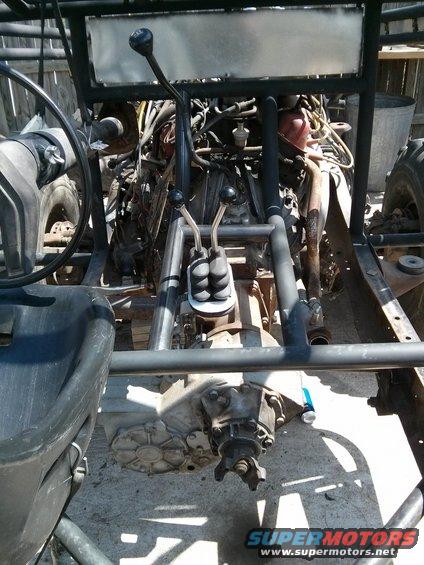 Interior view of vehicle with exposed engine, transmission, and roll cage