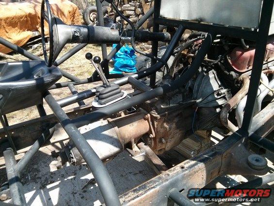 Off-road vehicle chassis showing transmission, steering column, and shifter. Frame is exposed