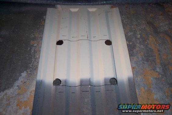 Metal panel with four circular cutouts and drawn lines, showing ribbed texture