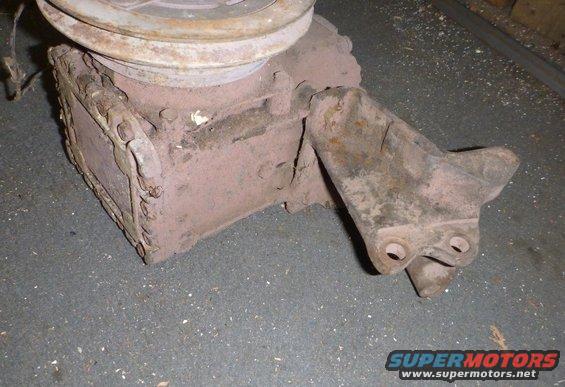 Rusty automotive part, possibly a pump, with a pulley attached