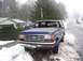 1988 Ford Bronco - A blue Ford Bronco is parked on a snowy road next to a house, with a black pickup truck visible behind it.