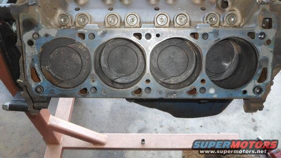 Engine block with four pistons visible, on a stand
