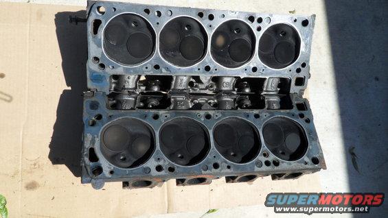 Two engine cylinder heads stacked on top of each other, showing the combustion chambers and valve stems