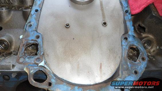 Engine block with timing cover gasket removed, showing bolts and part of the timing cover