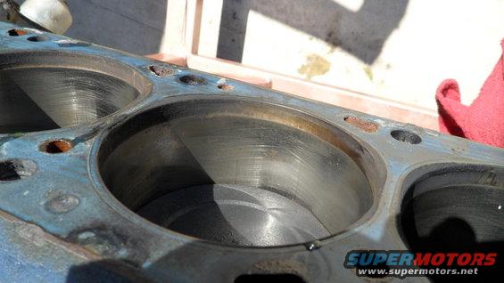 Engine block with three cylinders visible, showing wear marks and rust spots