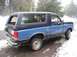 1988 Ford Bronco - Side view of a damaged blue and dark blue Ford Bronco parked outdoors in winter.
