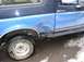 1988 Ford Bronco - The rear quarter panel of the SUV shows extensive damage and rust, indicating a past collision or neglect.