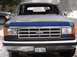 1988 Ford Bronco - This 1988 Ford Bronco is seen from the front, its distinctive grille and a blue hood protector. A second vehicle is partially visible to th…
