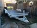 2014 Transnational Firestar 150CC - A white utility trailer with a wooden deck and a spare tire is parked outdoors.