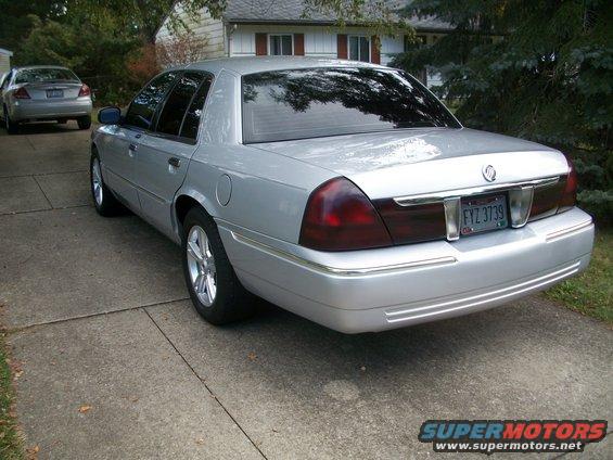 Silver 2003 Mercury Grand Marquis sedan parked on driveway, rear 3/4 view