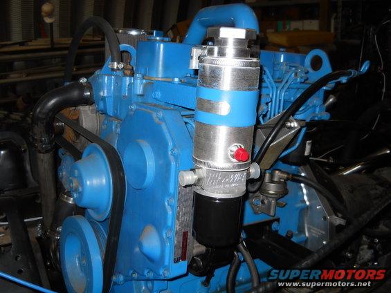 Blue engine block with silver and blue oil filter assembly and black hoses