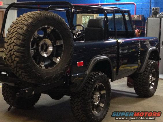 Dark blue 1970 Ford Bronco with a spare tire mounted on the rear, aftermarket wheels, and a roll cage