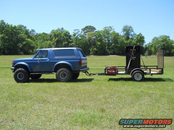 1992 Ford Bronco, lifted, with aftermarket wheels, towing a utility trailer carrying a safe and other items