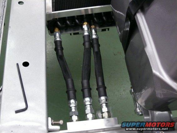 Brake lines connect to a radiator assembly. A hex wrench rests on a metal bracket