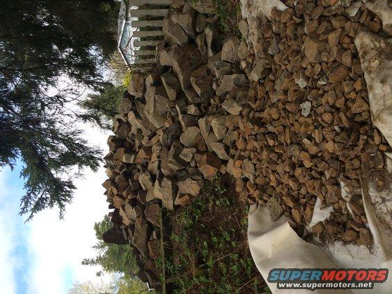 Pile of rocks next to a white fence and trees