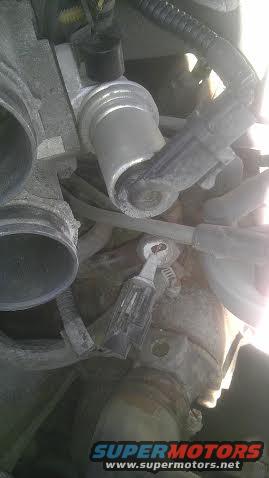 Close-up of an engine component with hoses and wires