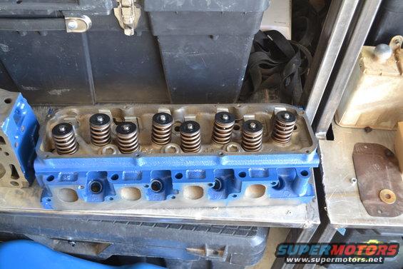 Blue painted engine cylinder head with valve springs visible