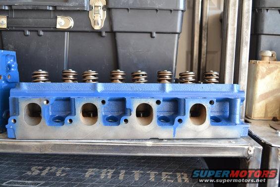 Blue engine cylinder head with valve springs visible