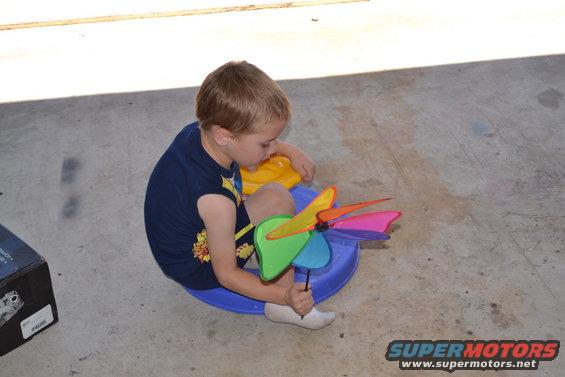 Boy playing with a colorful pinwheel on a concrete surface